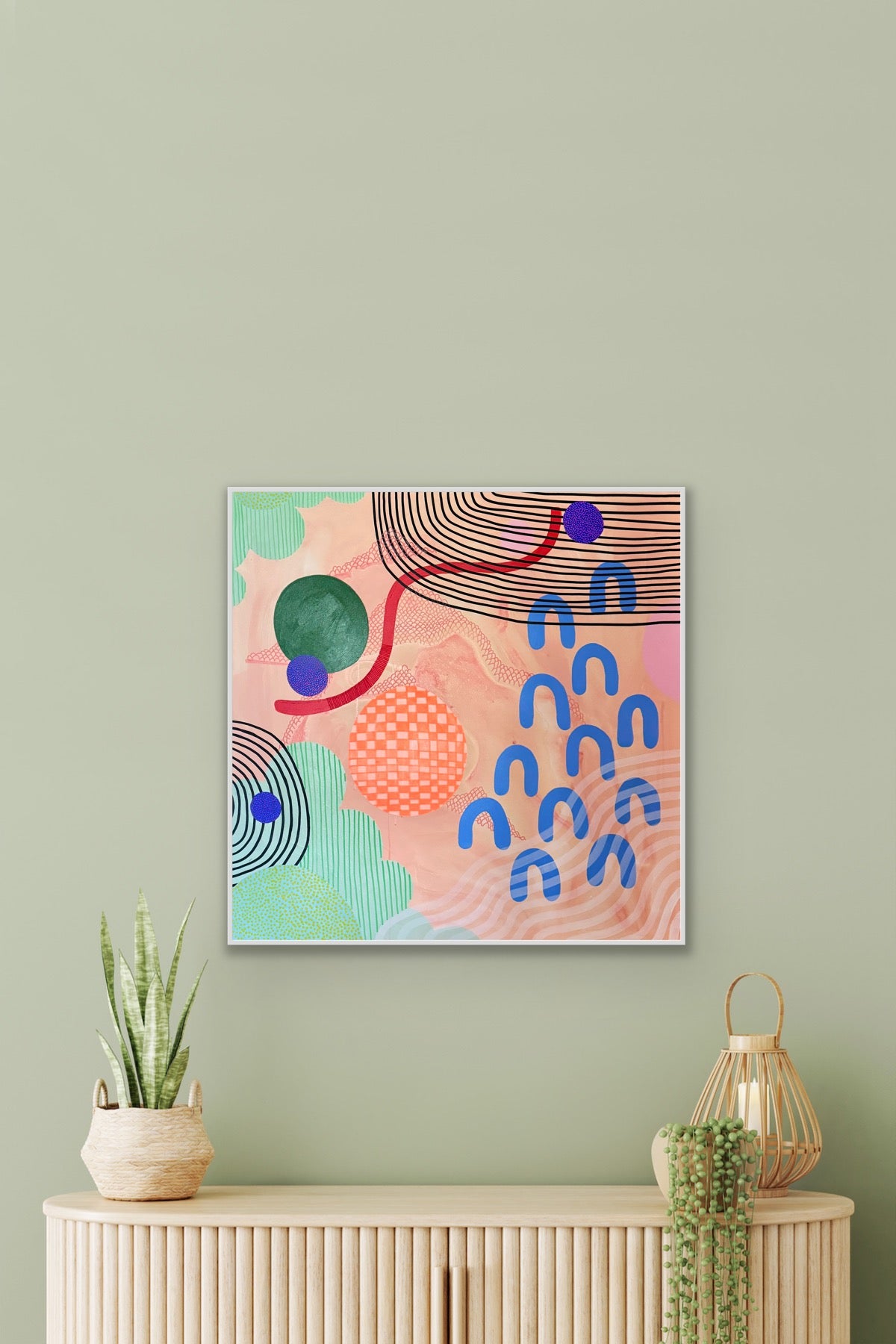 Abstract art print on a wall above a wooden console table with decorative items.